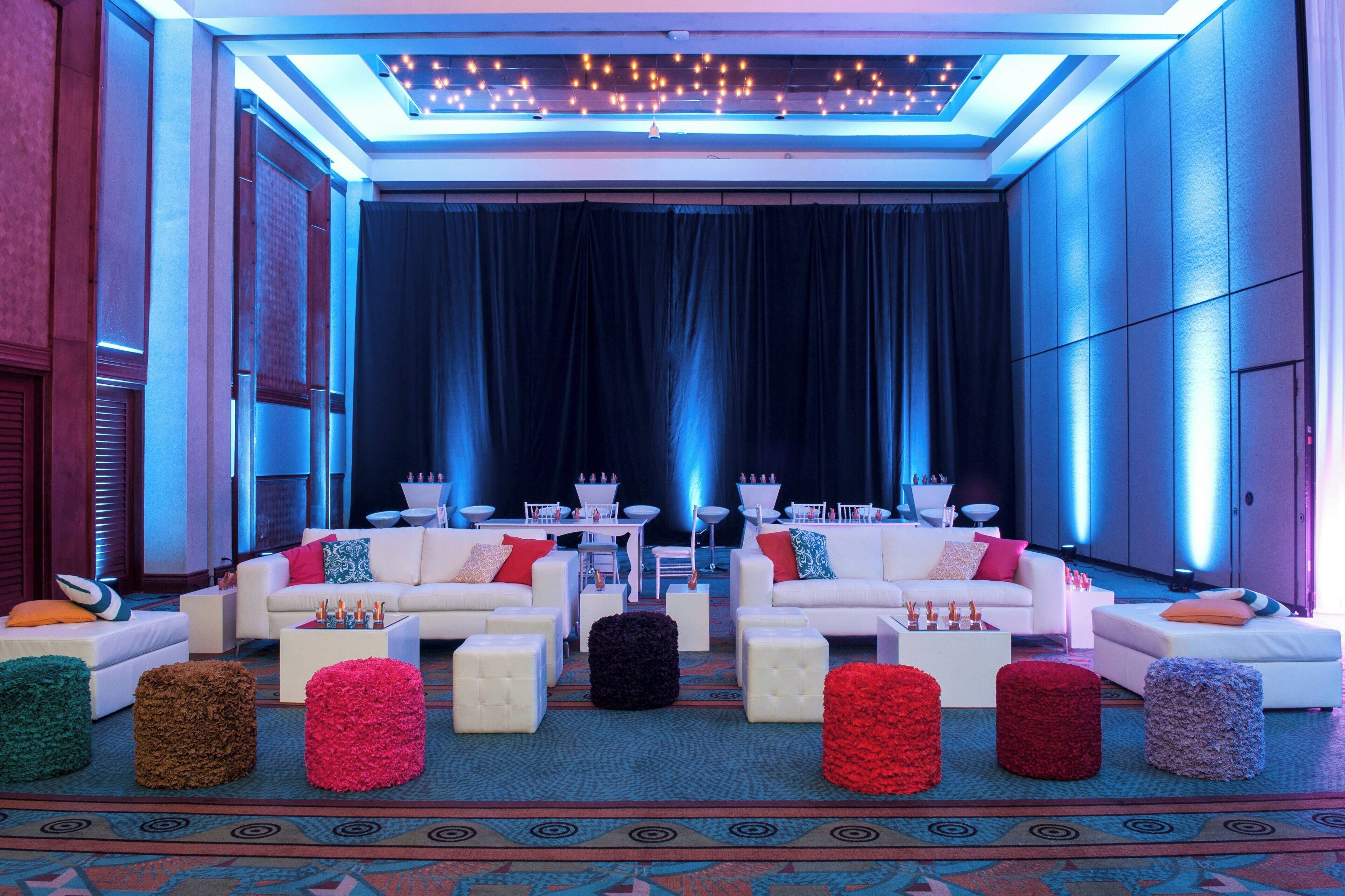 Un espace de détente moderne avec des canapés blancs, une moquette à motifs et un éclairage décoratif.