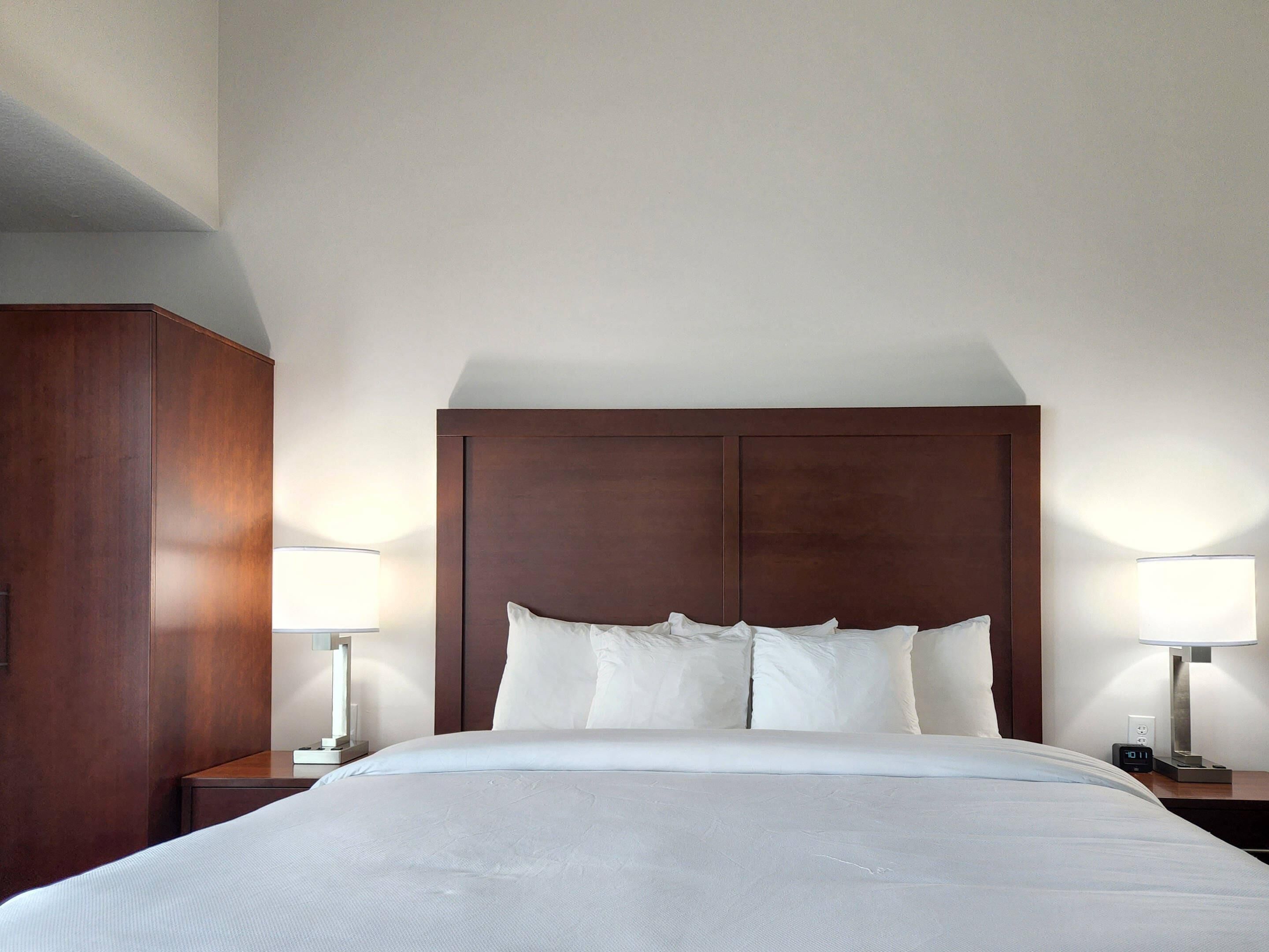 Una habitación de hotel con una cama grande, dos mesitas de noche y un armario de madera.