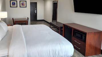 Habitación de hotel con cama, escritorio, silla, televisor y microondas.