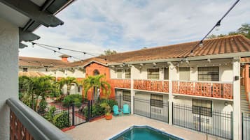 A courtyard with a swimming pool, outdoor seating, and a multi-story building with balconies.
