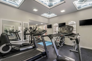 A modern interior with two large beverage refrigerators, a small cooler, and a flat-screen TV on a wooden shelf. at Clarion Pointe Tampa-Brandon Near Fairgrounds and Casino