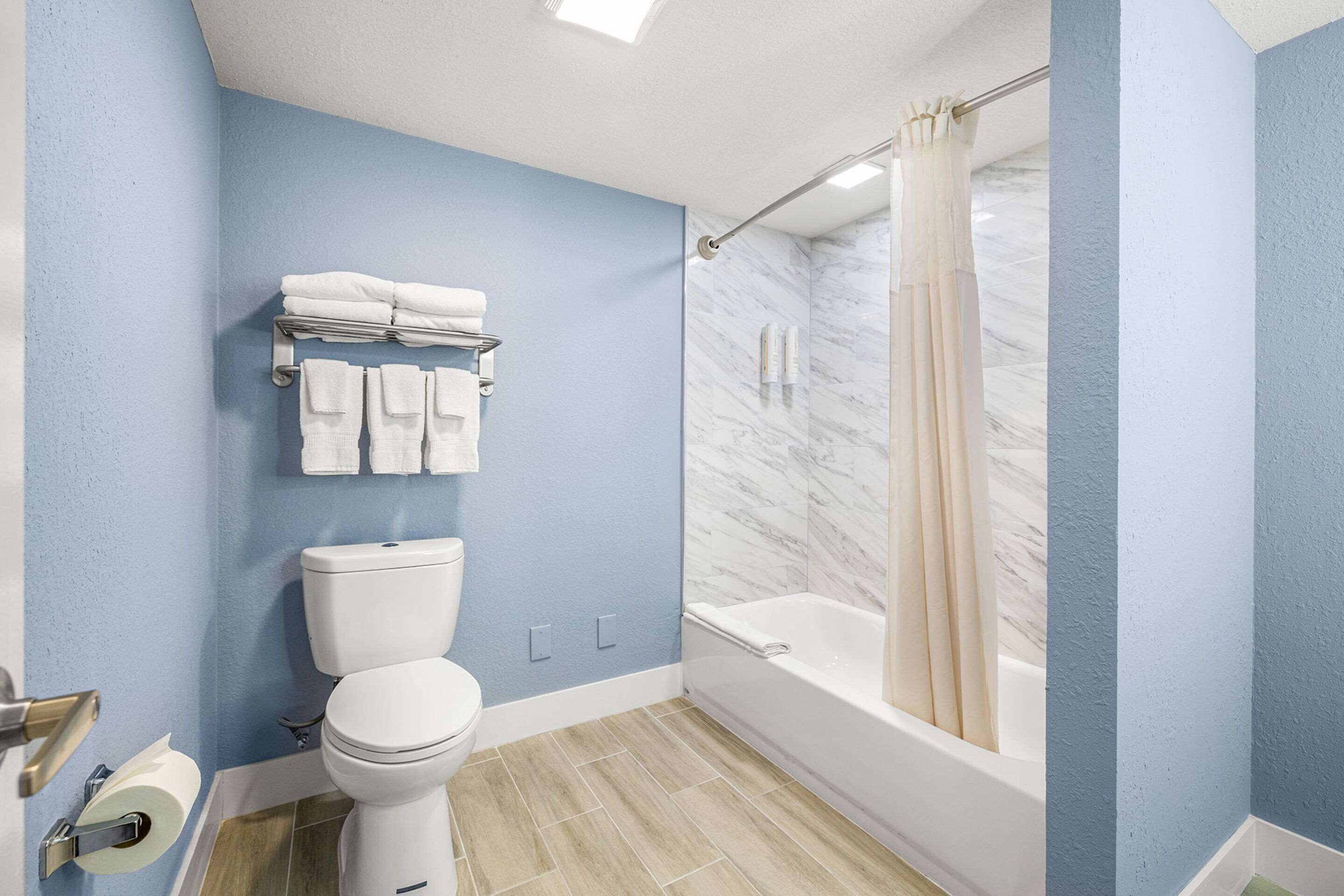 Un baño con inodoro, lavamanos, bañera y cortina de ducha.