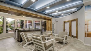 Zona d'estar àmplia amb un sostre alt, prestatges de fusta integrats i una illa central.