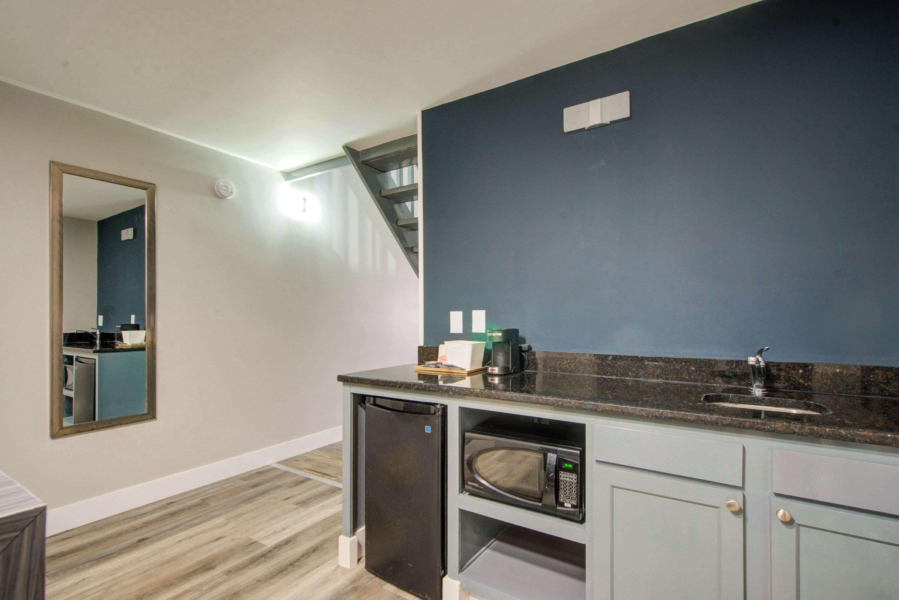 A compact kitchen with a built-in microwave, a coffee maker, and a sink.