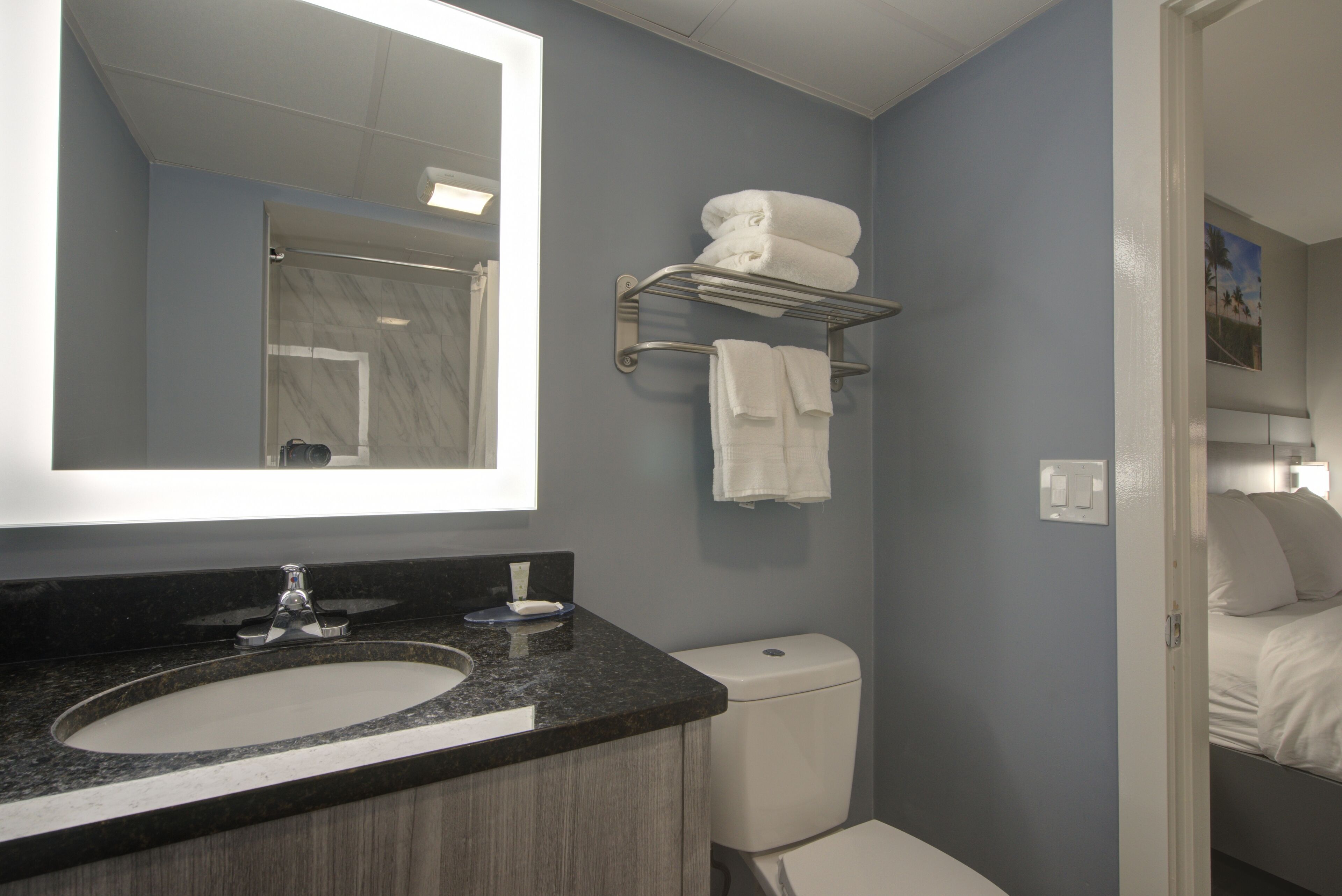 Une salle de bain équipée d’un lavabo, d’un miroir, d’un porte-serviettes et de toilettes.