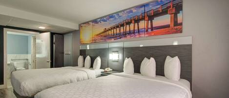 Habitación de hotel con dos camas, un cuadro grande de un muelle y vistas al mar. Incluye un baño.