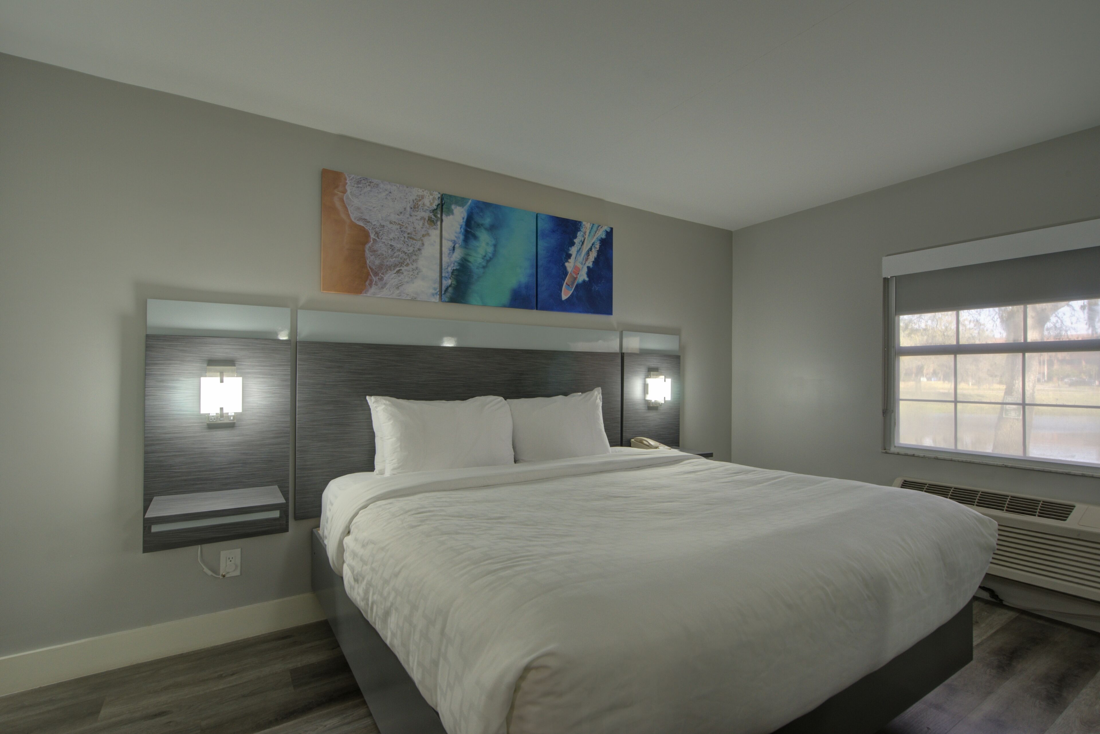 Ein modernes Schlafzimmer mit einem großen Bett, Nachttischen und einem an der Wand hängenden Kunstwerk.