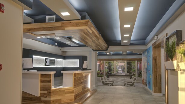 Una zona de recepció amb taulell de fusta, espai per seure i vistes a l'exterior.
