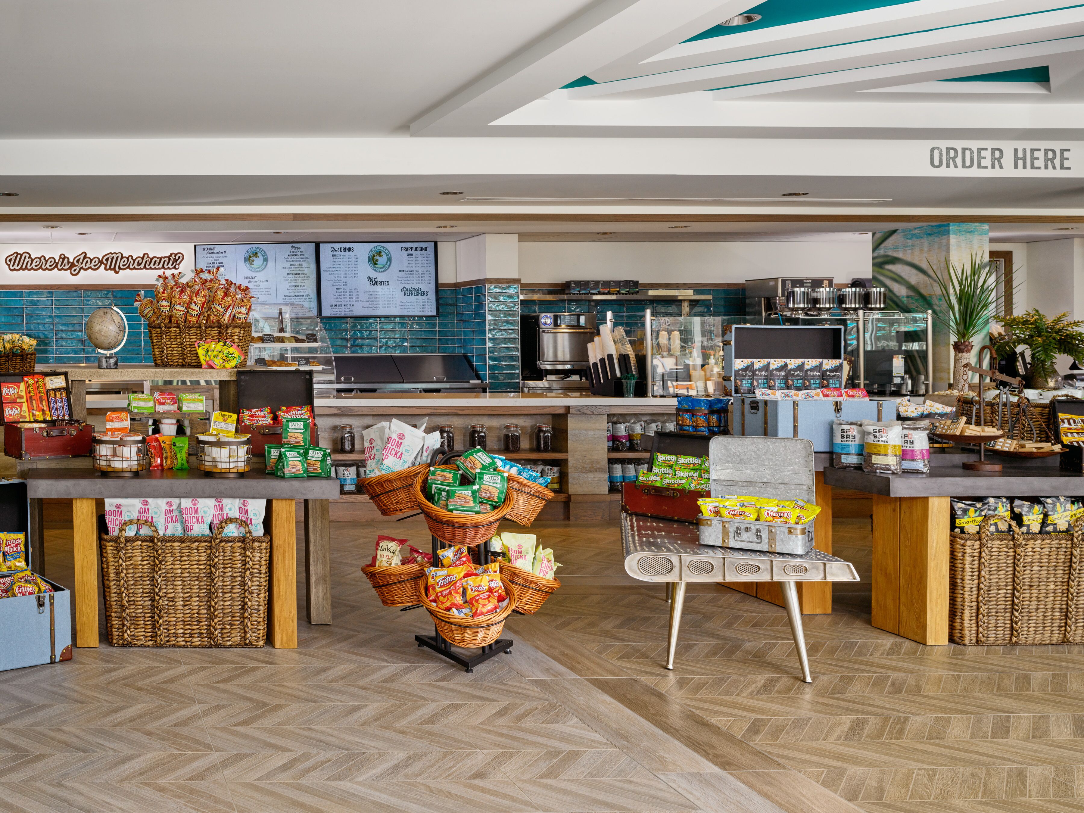 A cafe with a variety of snacks and beverages, a counter for ordering, and a menu board.