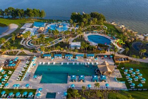 An aerial view of a resort with multiple swimming pools, sun loungers, and palm trees. - Margaritaville Lake Resort, Lake Conroe/Houston (Montgomery)