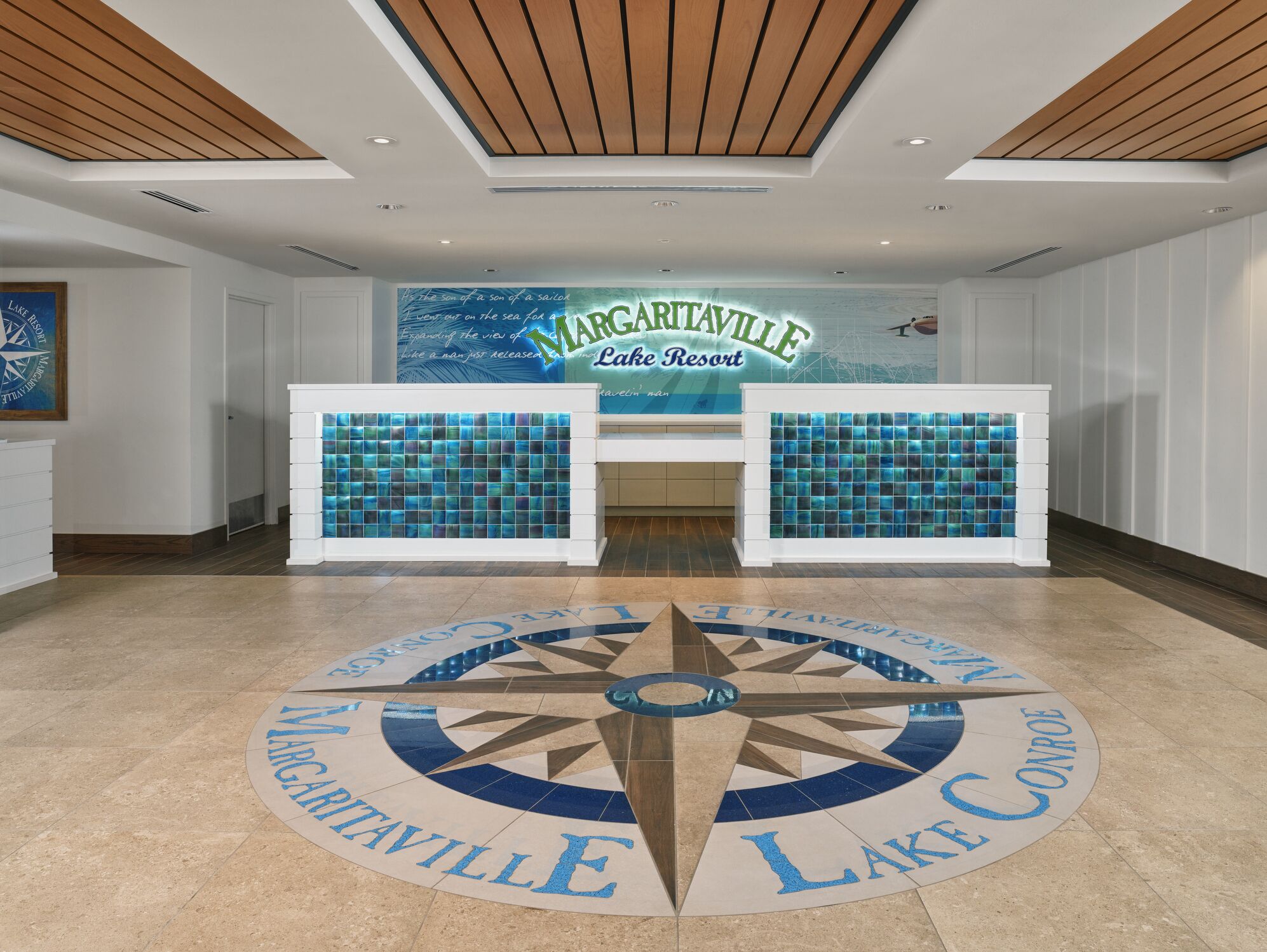 A reception area with a large sign reading "Margareville Lake Resort" and a circular floor design with "Margareville Lake" and "Lake Conway" inscribed.