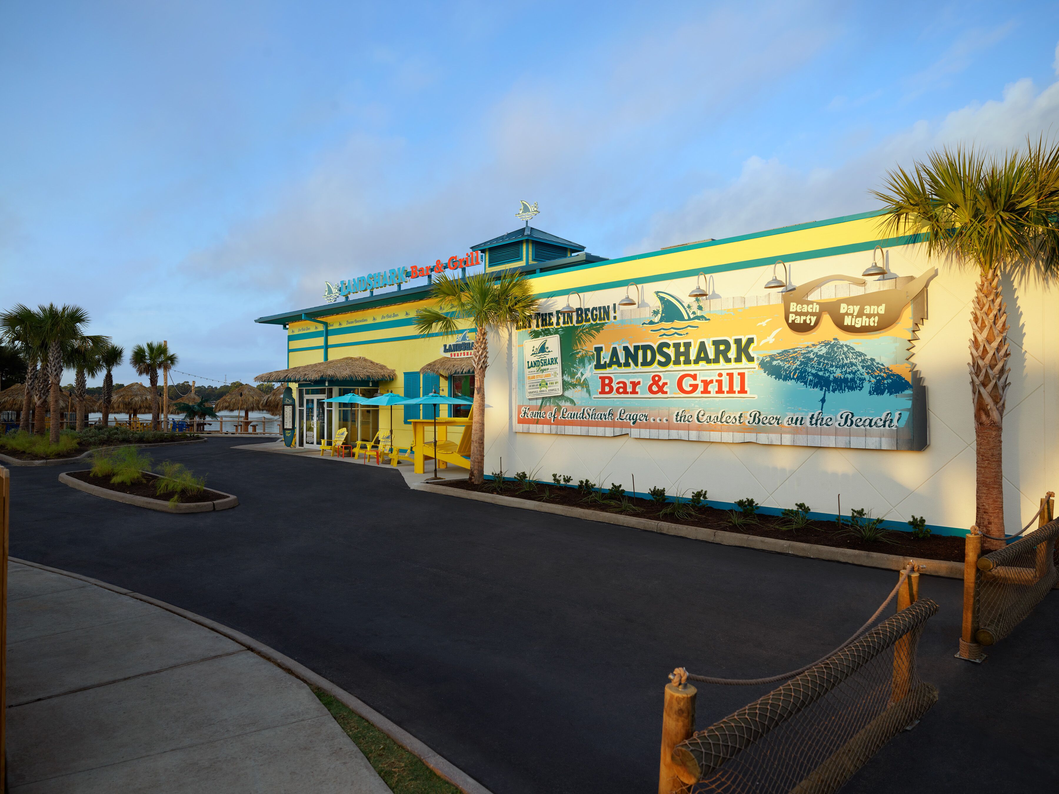 A beachfront bar and grill with a large sign advertising its name and offerings.