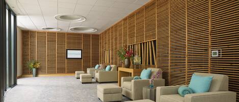 A modern spa area with seating, a screen displaying 'ST. SOMEWHERE SPA', and a bamboo wall.