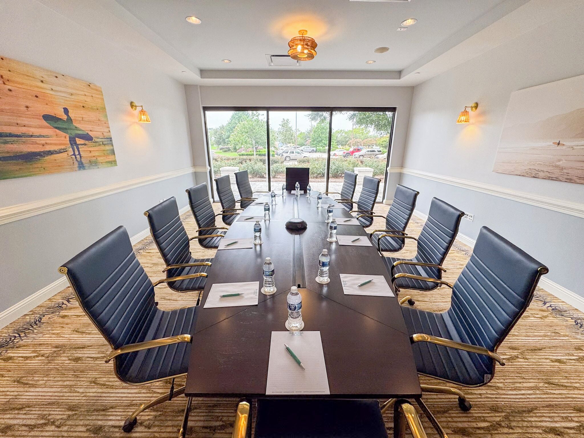 A conference room with a long table, black chairs, and water bottles.