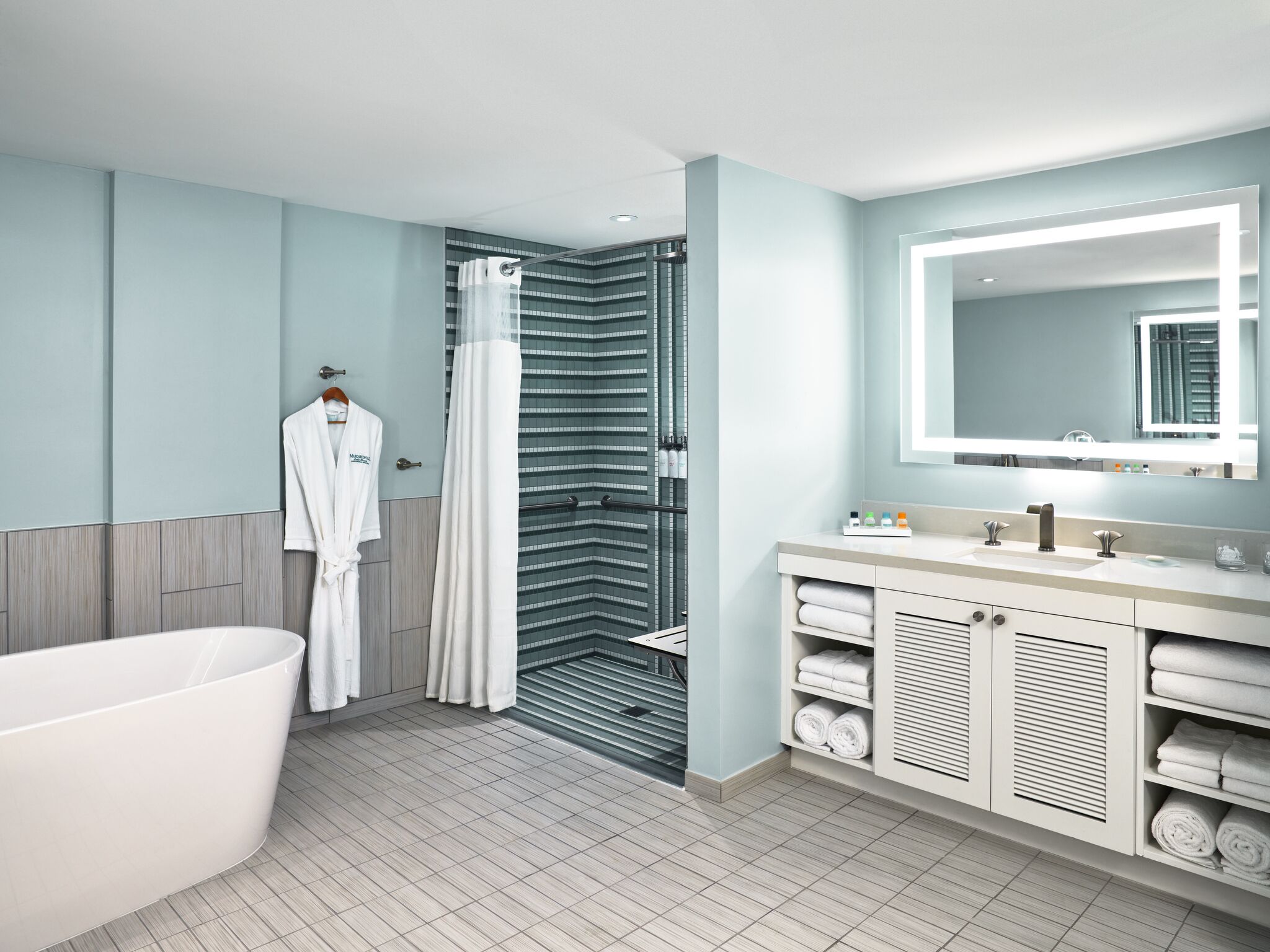 A modern bathroom with a freestanding bathtub, a shower with a glass door, and a vanity with a large mirror.