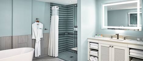 A modern bathroom with a freestanding bathtub, a shower with a glass door, and a vanity with a large mirror.
