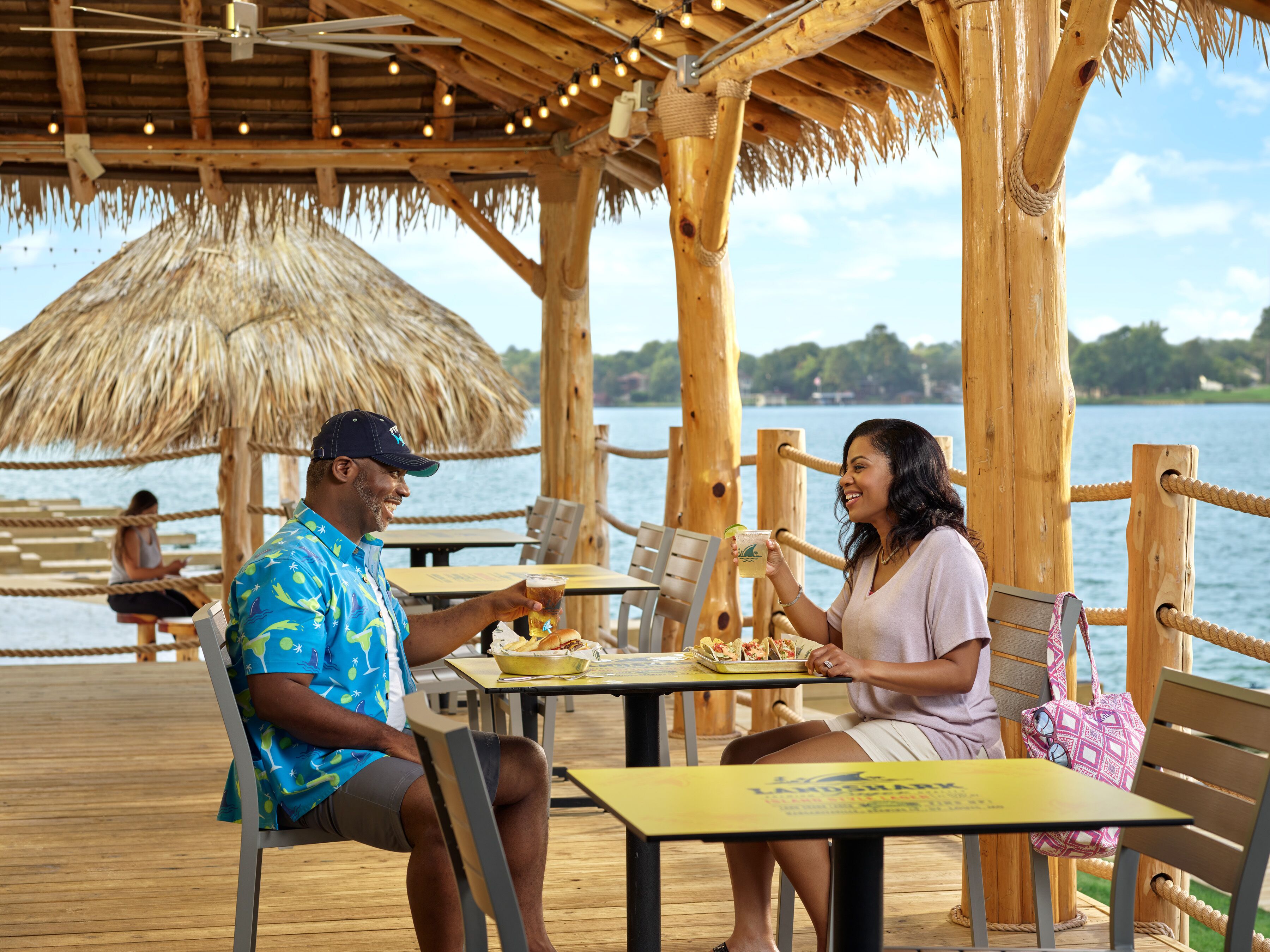 A wooden deck with tables and chairs, overlooking a body of water.