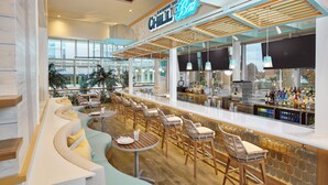 A bar area with a curved seating arrangement, a bar counter with a variety of bottles, and a sign that reads "Chill Bar". - Margaritaville Lake Resort, Lake Conroe/Houston (Montgomery)