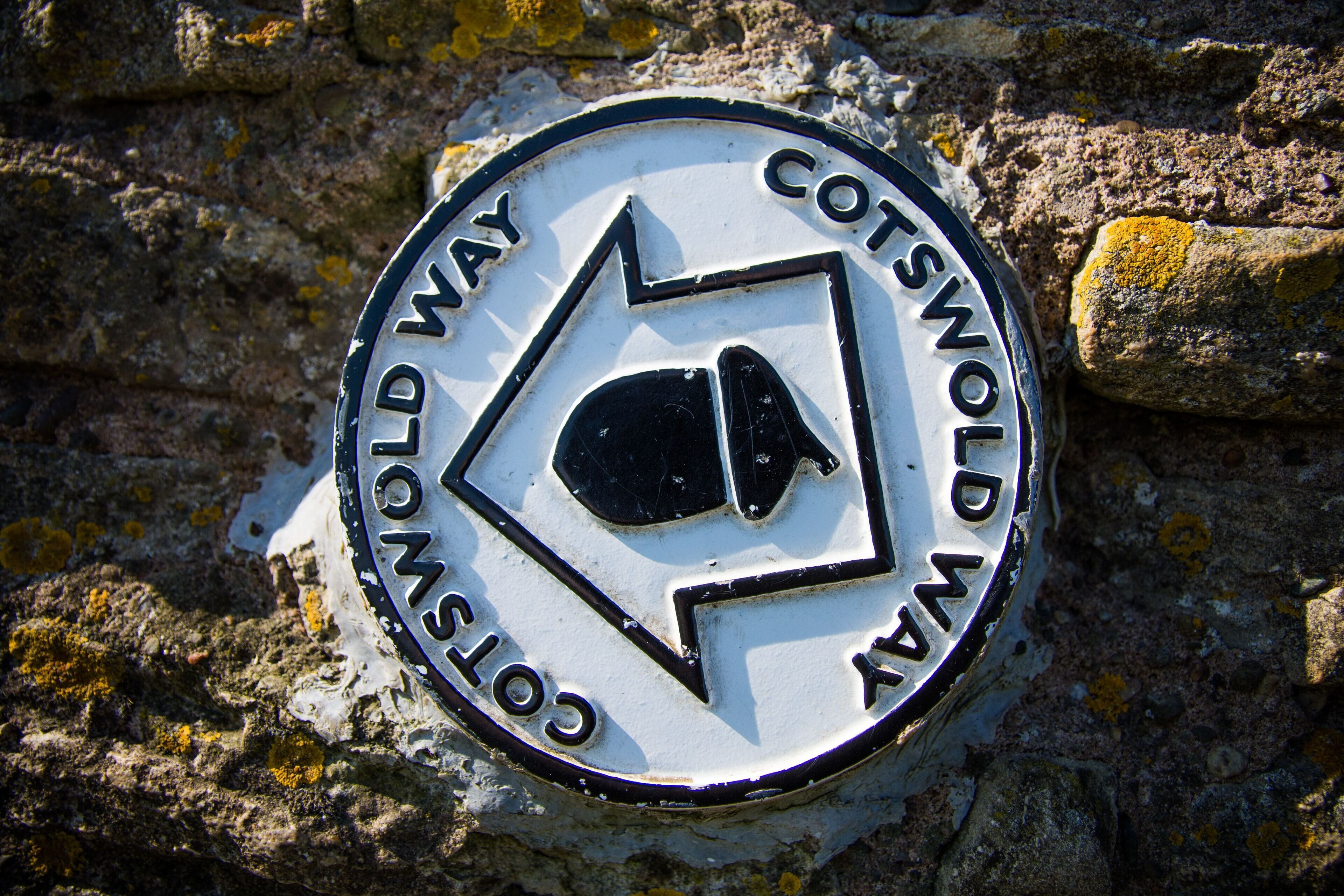 A circular sign with the text "Cotswold Way" and a directional arrow.