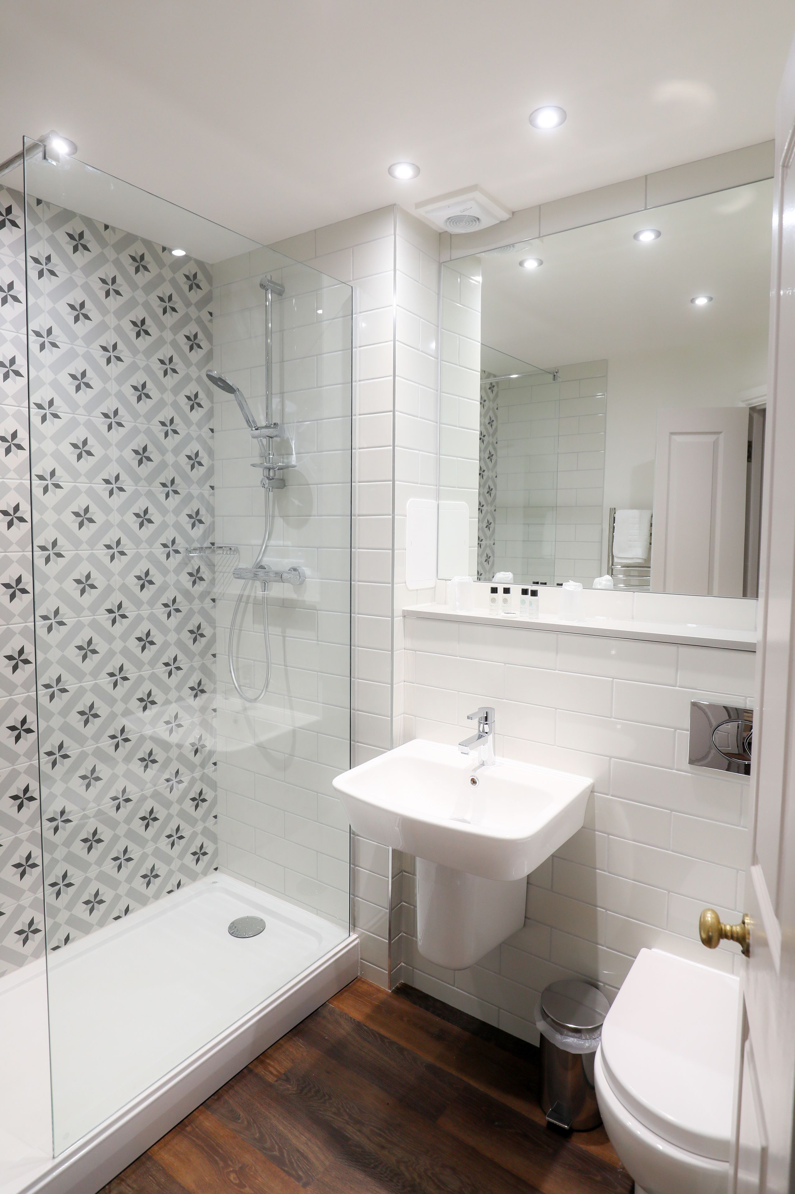A modern bathroom with a glass shower enclosure, a white sink, and a toilet.