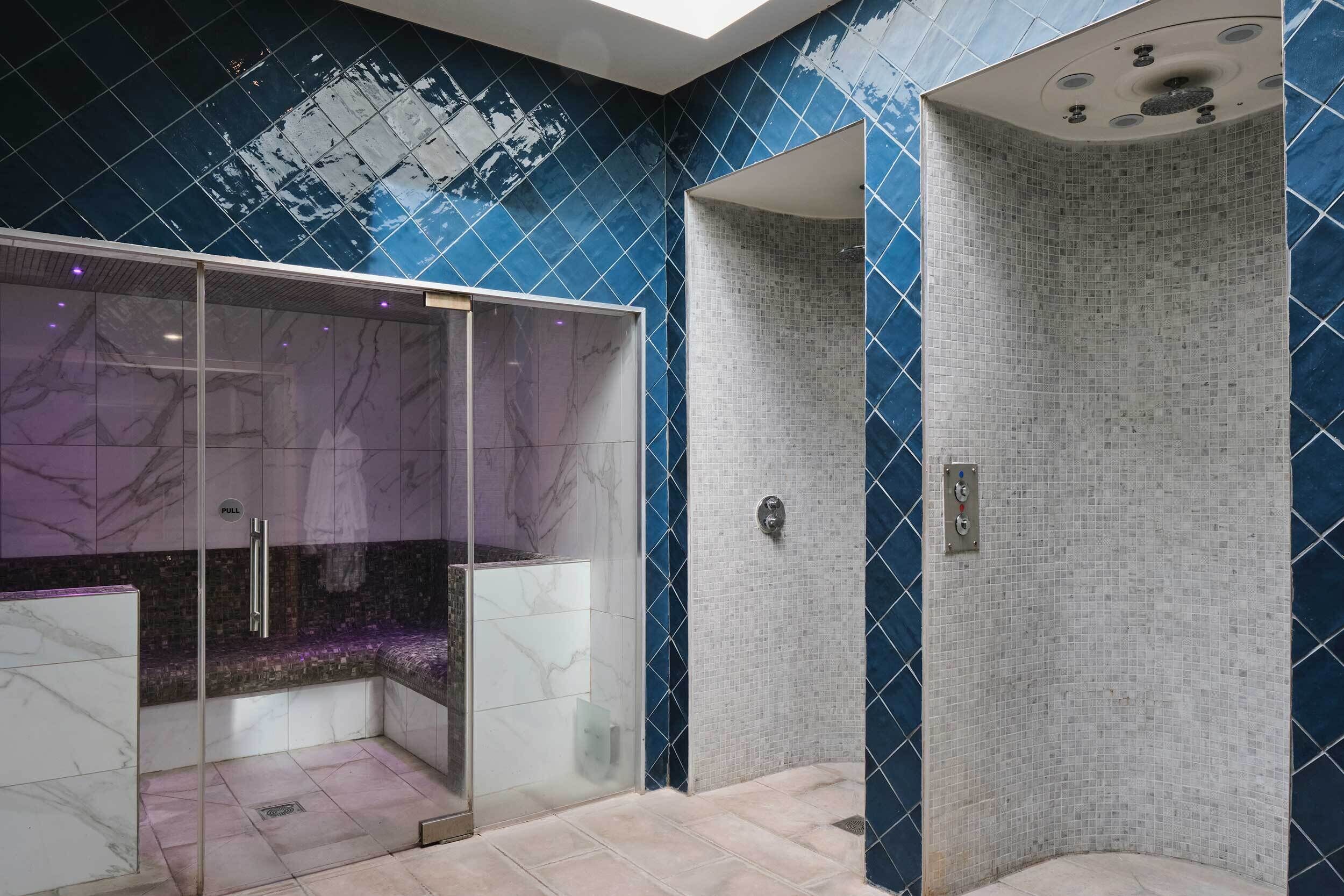 A modern bathroom with a glass-enclosed shower, a marble vanity, and a tiled shower area.