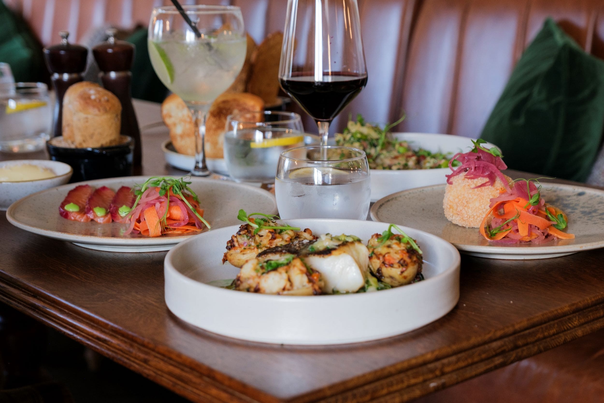 A dining table with various dishes, including seafood, salads, and bread.