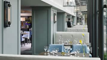 Un comedor con una mesa dispuesta para comer, un camarero al fondo y vista del interior del restaurante.
