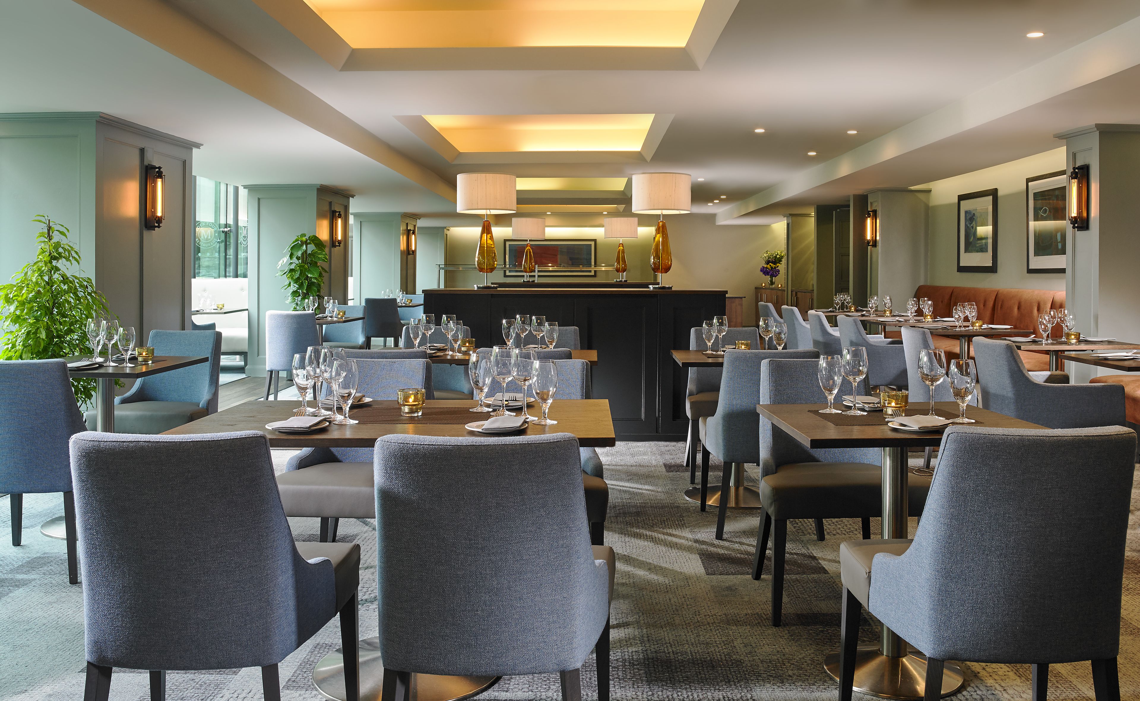 Un restaurante moderno con varias mesas y sillas, una zona de bar y una sección con asientos.