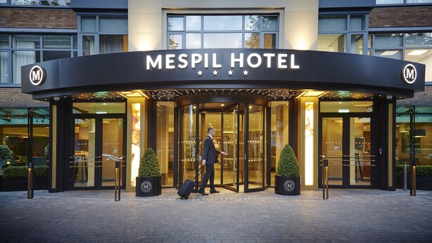 La façade extérieure de l’hôtel Mespil, avec son entrée, et un homme en costume qui s’y dirige.