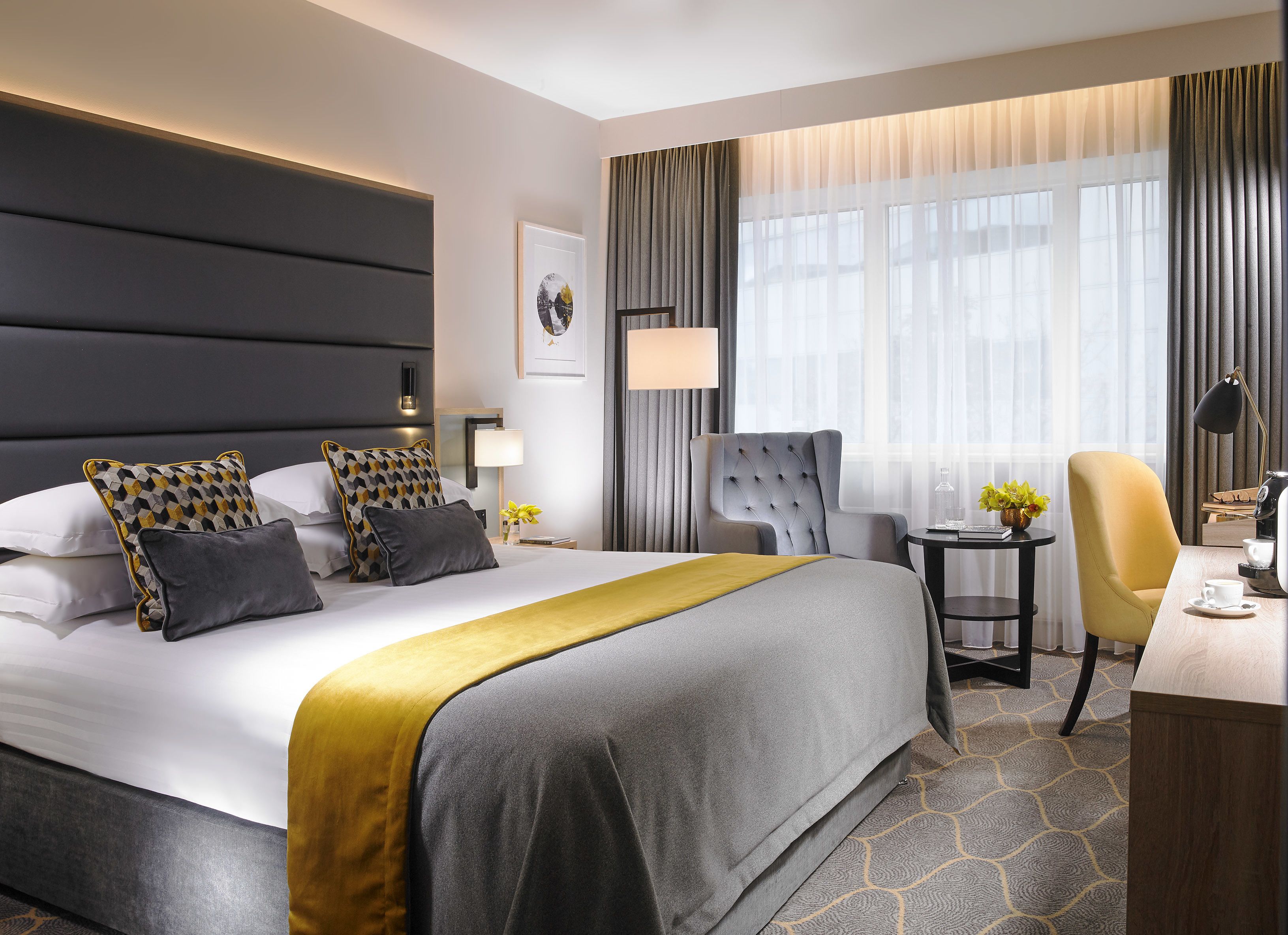 Quarto de hotel moderno com uma cama grande, uma escrivaninha e uma cadeira.