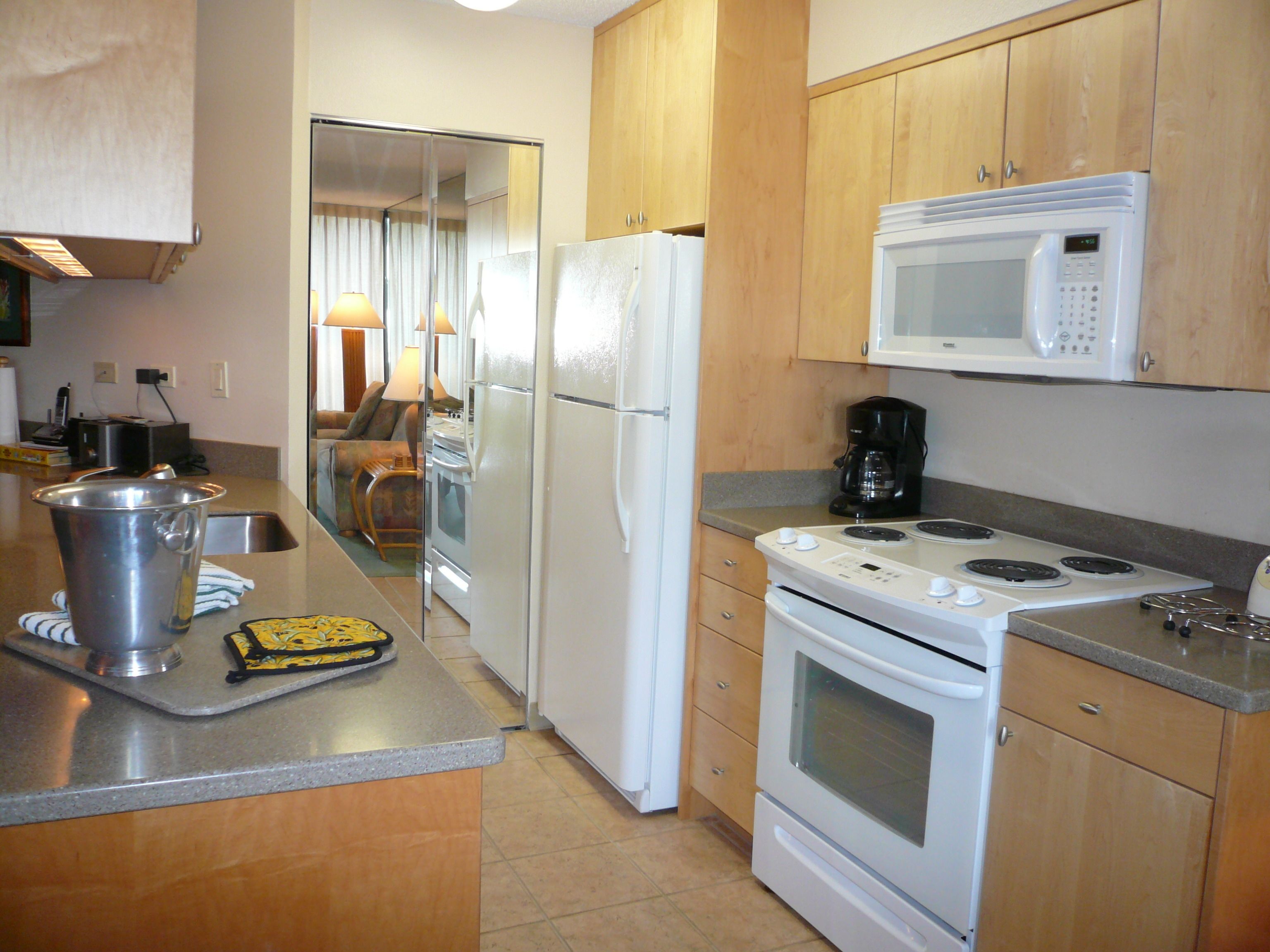 A compact kitchen with a refrigerator, microwave, stove, and sink.