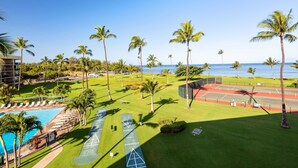 Un complexe hôtelier doté d’une piscine, de courts de tennis et de palmiers.