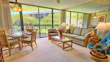 A spacious living room with a balcony, furnished with wicker chairs, a sofa, and a coffee table.