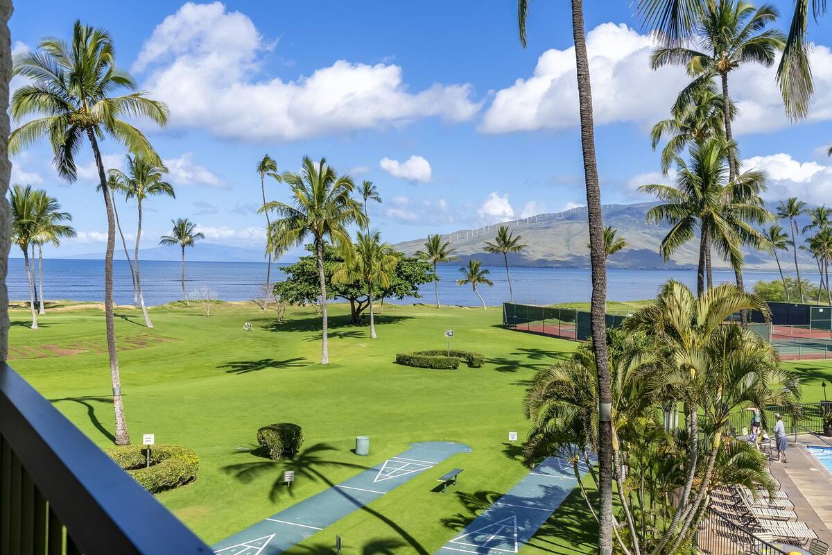 A golf course with palm trees and a view of the ocean.