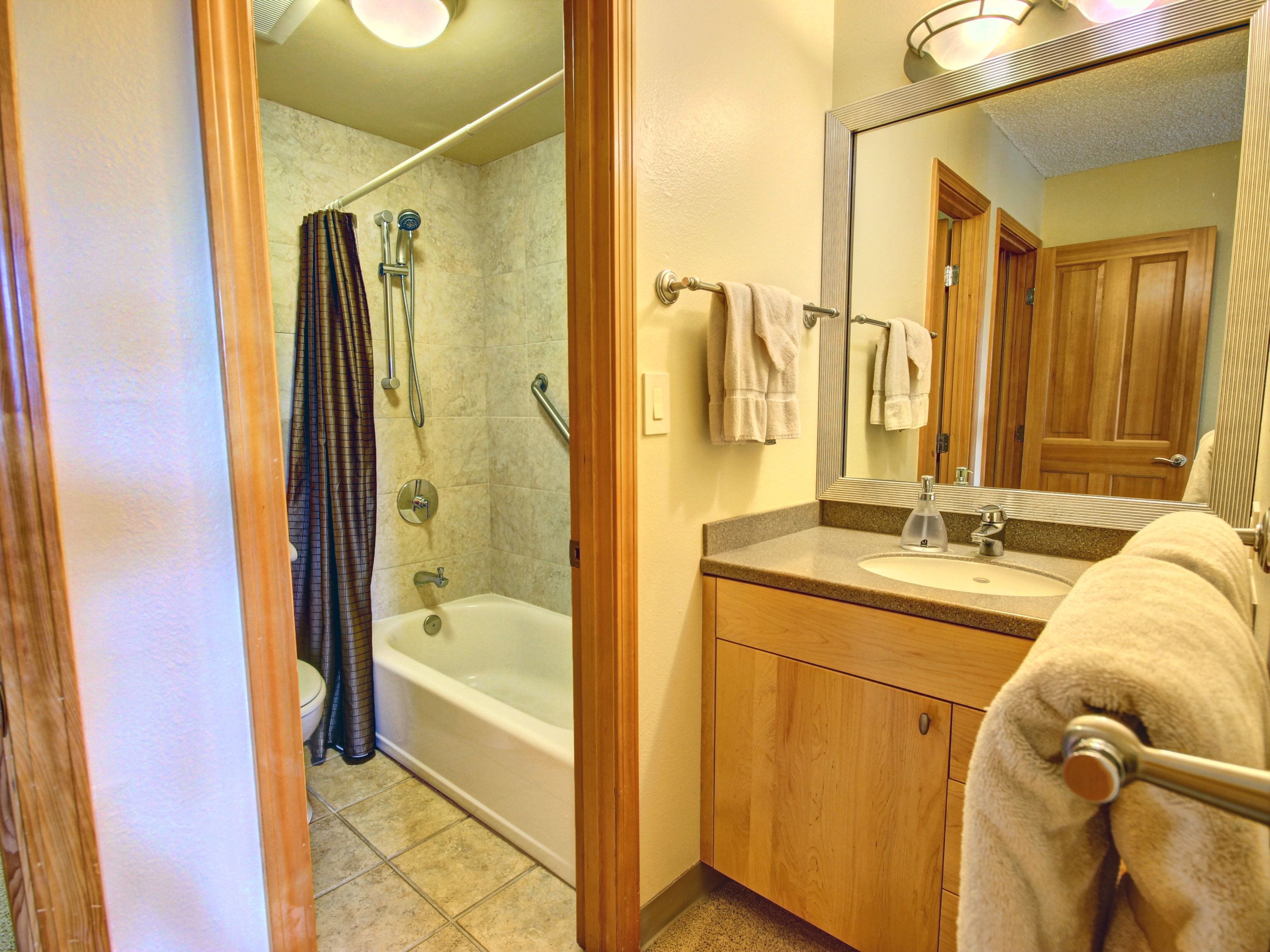 A bathroom with a bathtub, a shower, a sink, and a mirror.