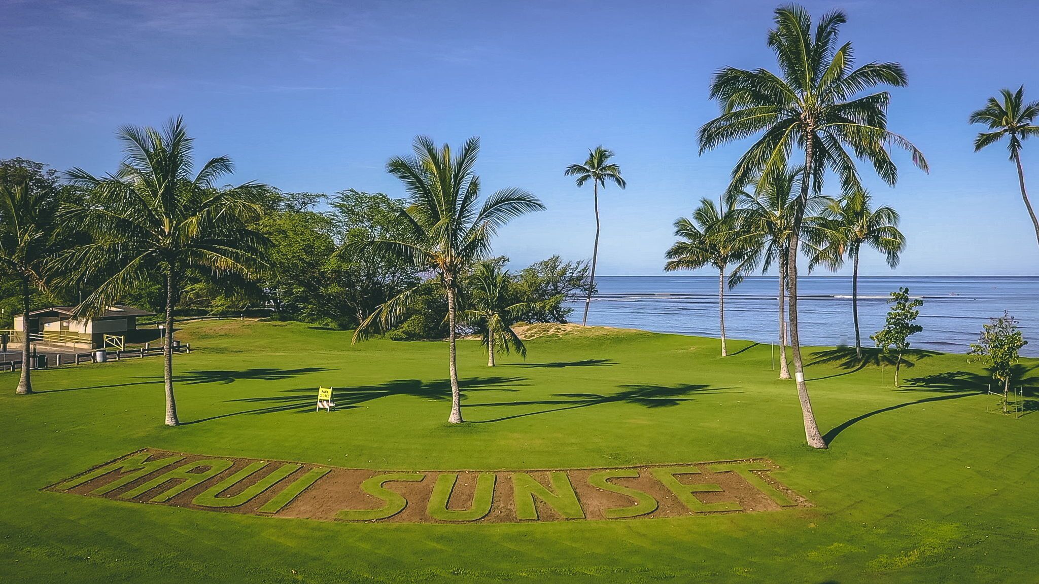 A golf course with a sign reading "CIRUS SUNSET" and a view of the ocean.