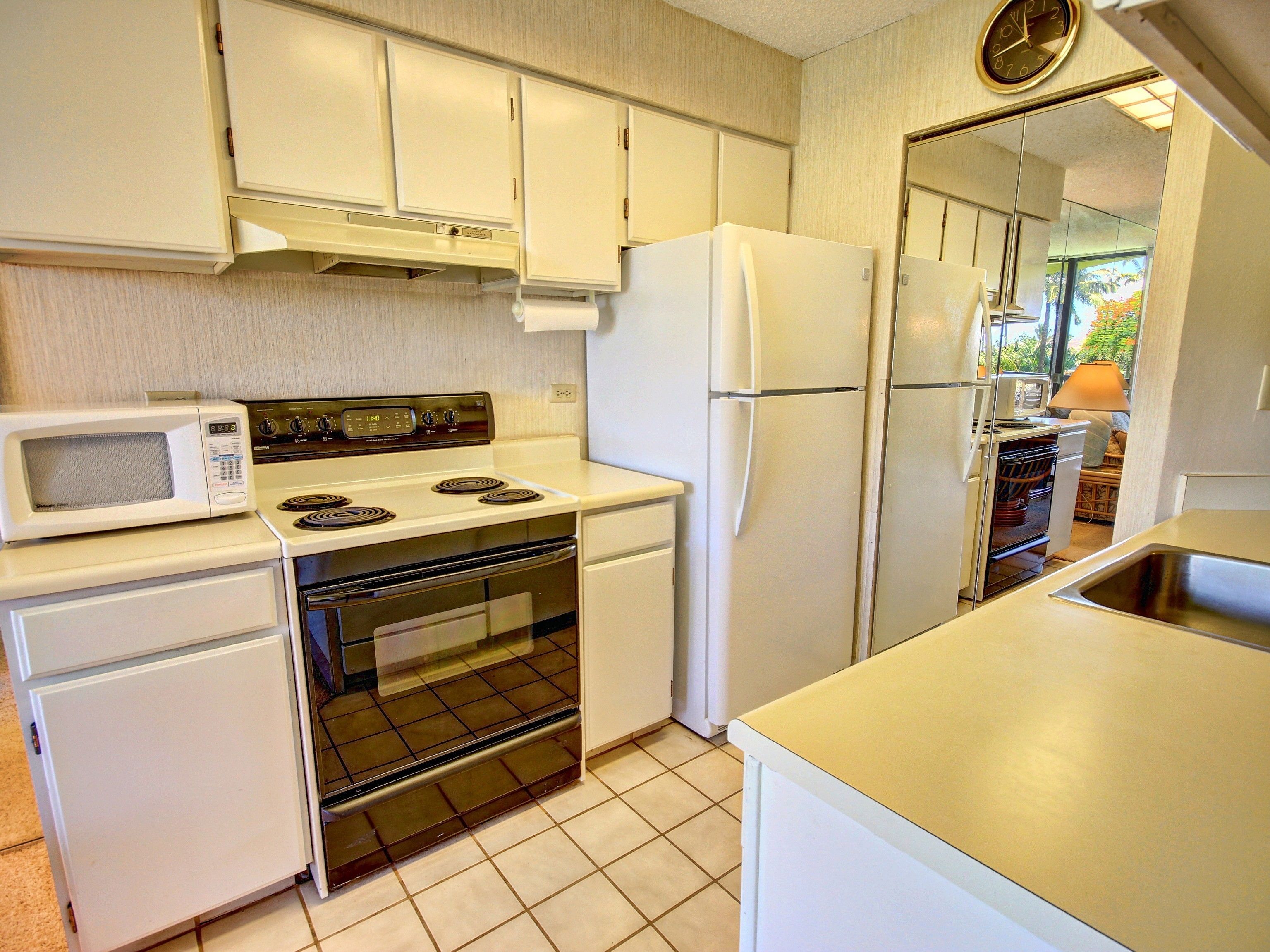 A compact kitchen with white appliances, including a stove, oven, microwave, and refrigerator.
