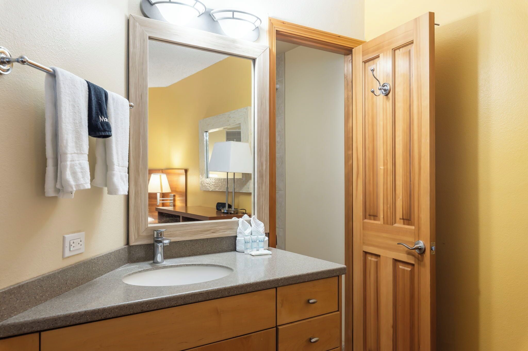 Une salle de bain avec un lavabo, un miroir, un porte-serviettes et une porte en bois.