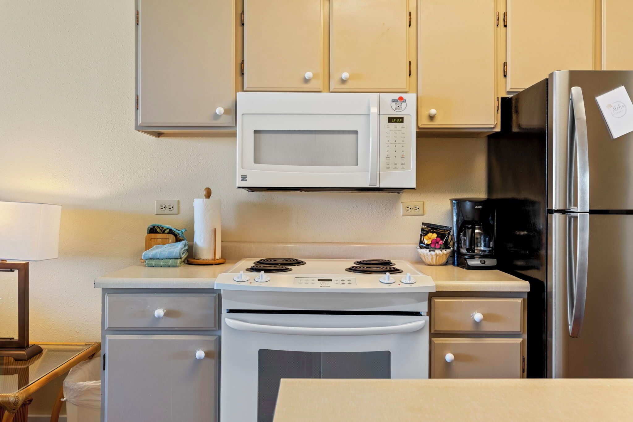 Una cucina compatta con un forno a microonde bianco, fornello e frigorifero in acciaio inossidabile.