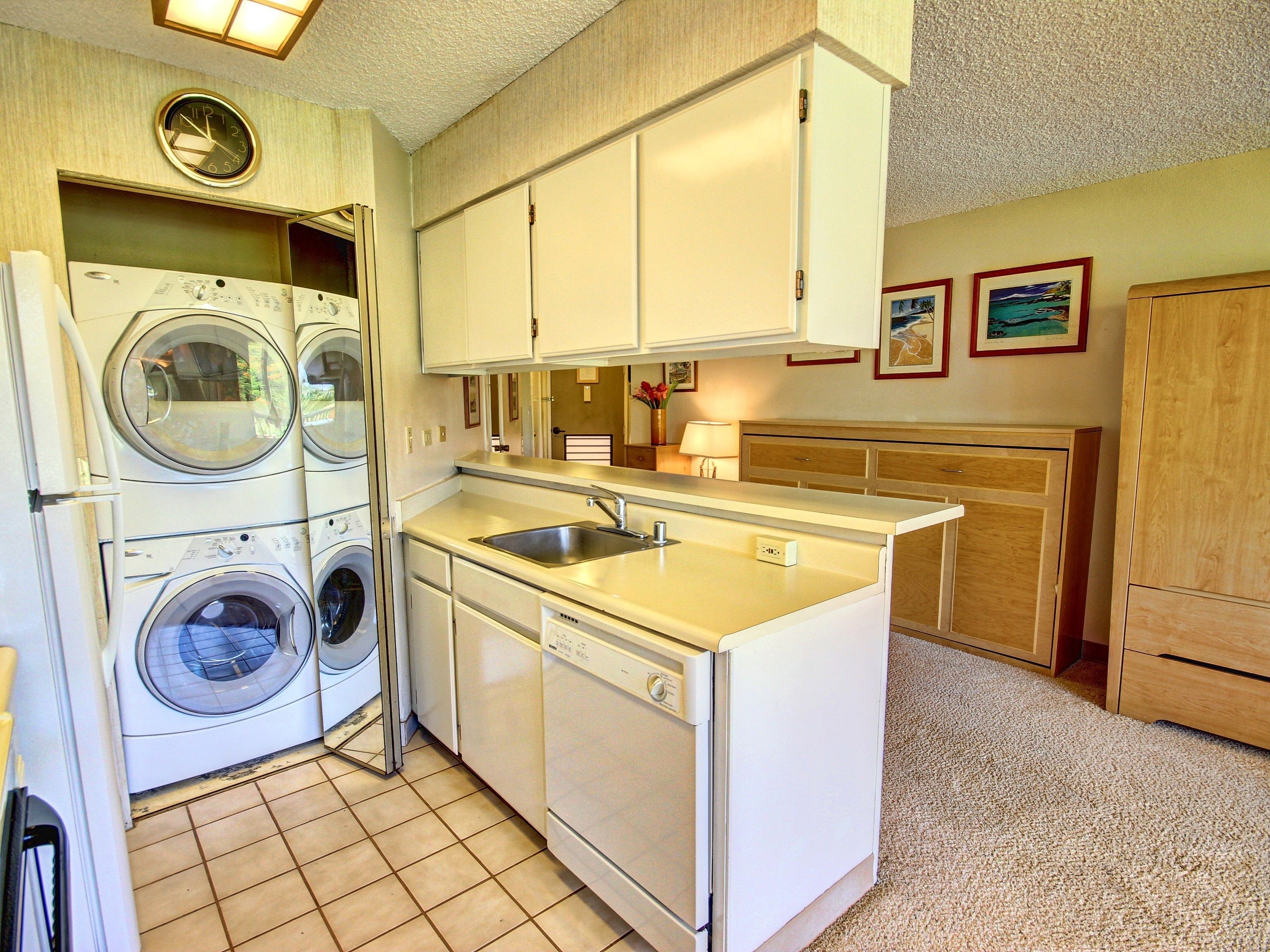 A compact kitchen with a built-in washer and dryer, a sink, and wooden cabinets.