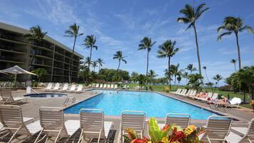 A swimming pool with lounge chairs and palm trees.