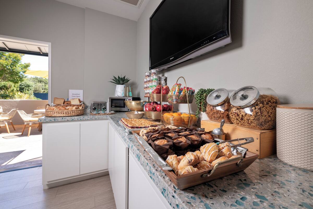 A breakfast buffet with various pastries, fruits, and beverages.