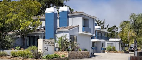 Un hôtel moderne à la façade bleue et blanche, doté d’un parterre aménagé et surplombant un ciel dégagé.