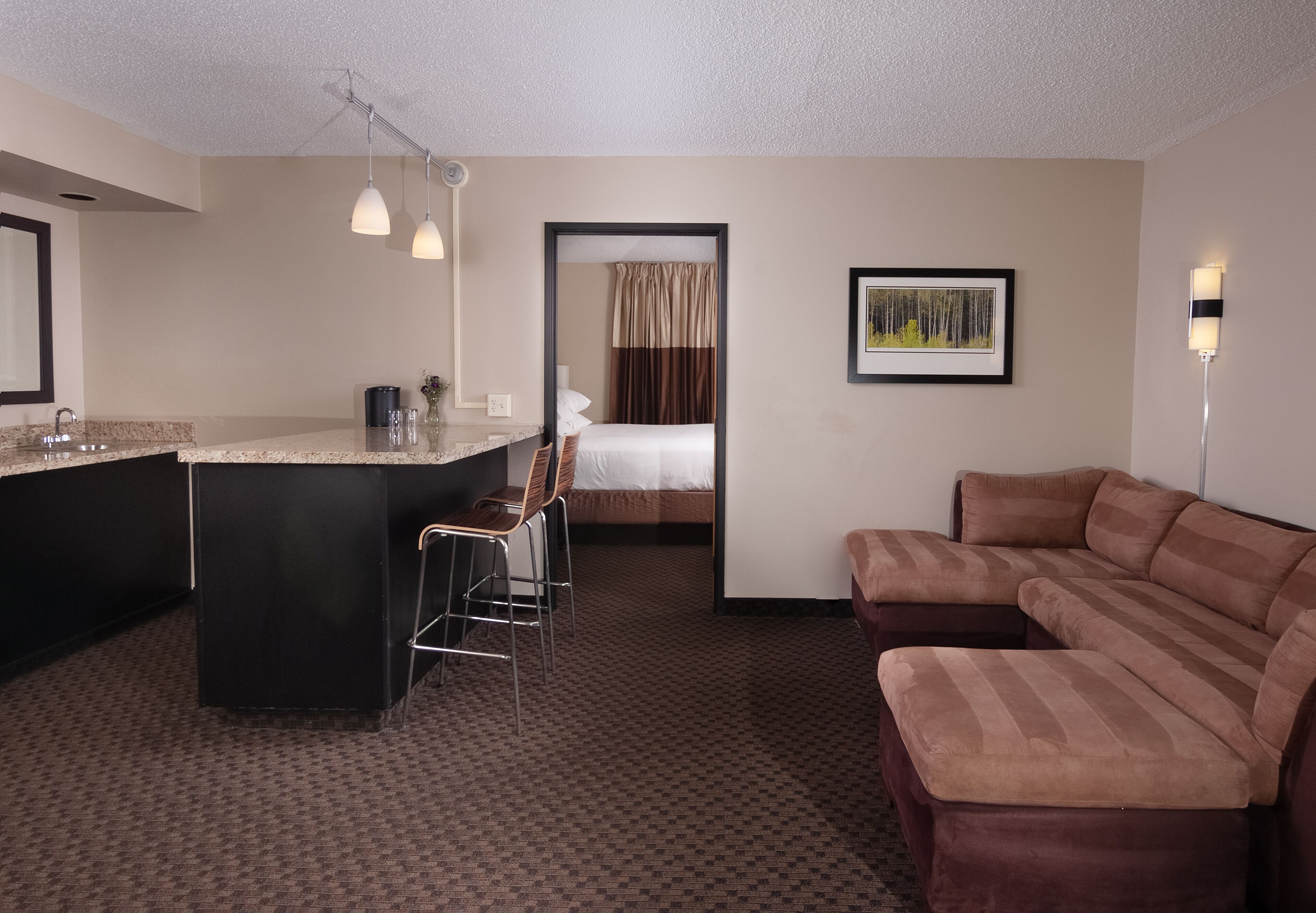 Habitación de hotel con kitchenette, cama, sofá y escritorio con sillas.