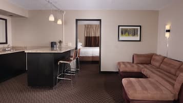 Habitación de hotel con kitchenette, cama, sofá y escritorio con sillas.