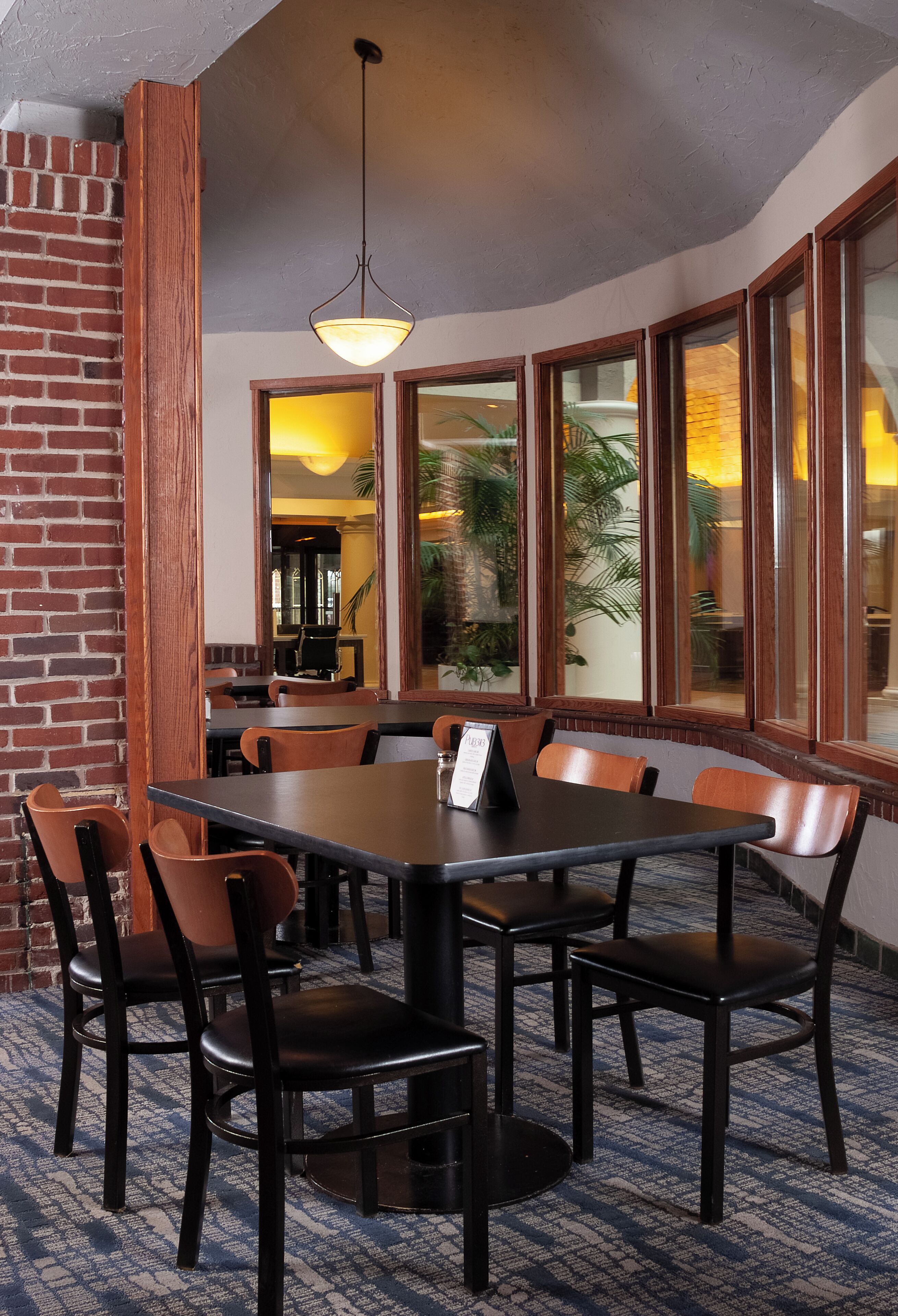 A restaurant with a brick wall, large windows, and a chandelier.