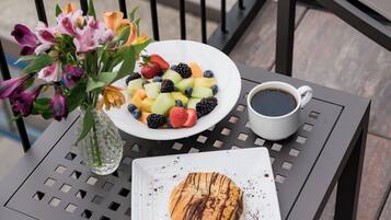 A table with a fruit salad, a cup of coffee, and a pastry.