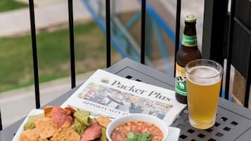 A table with a newspaper, a bottle of beer, a glass of beer, a bowl of salsa, and a plate of nachos.