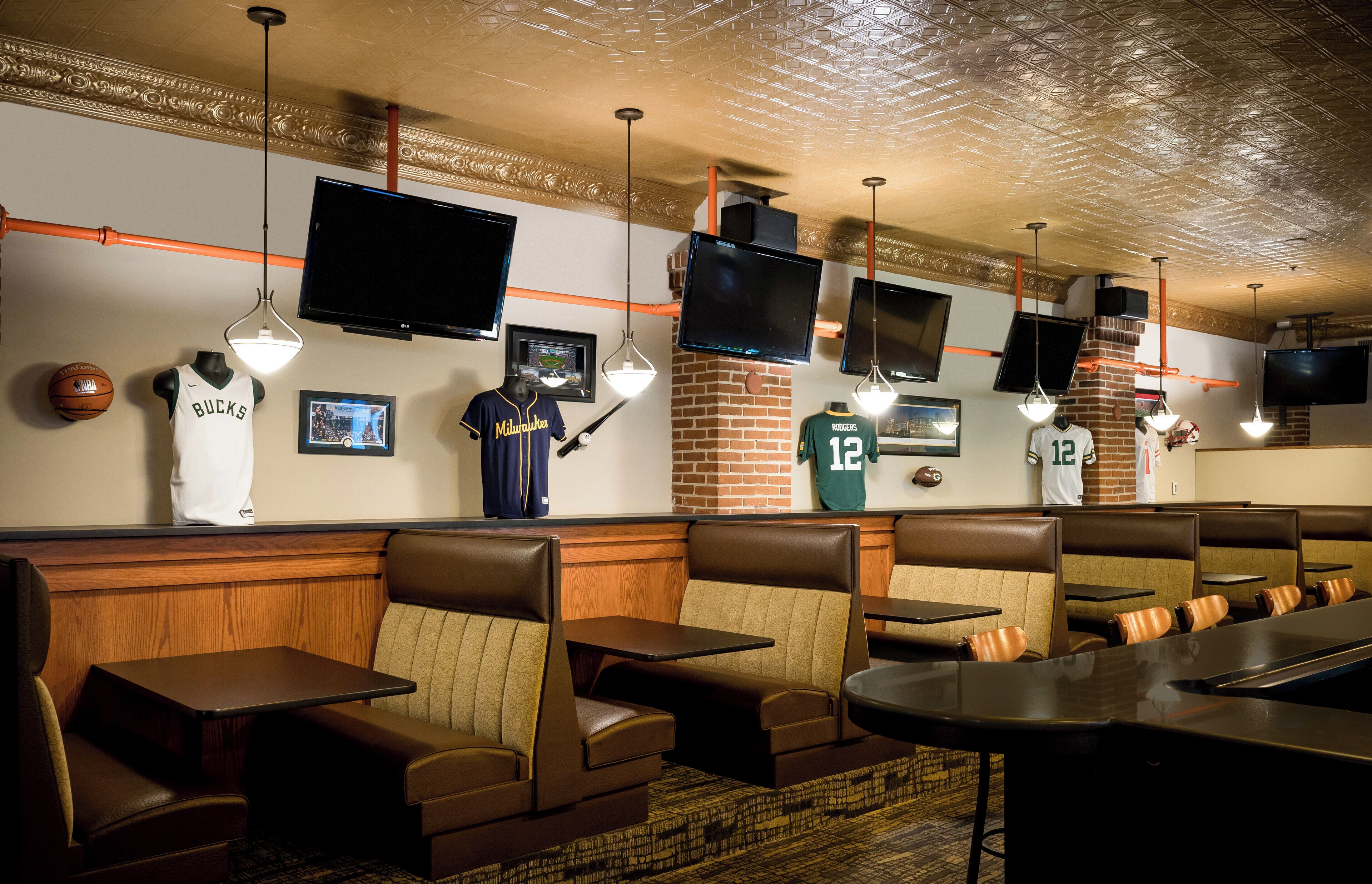 A sports-themed restaurant with leather booths, multiple TVs, and sports memorabilia on the walls.