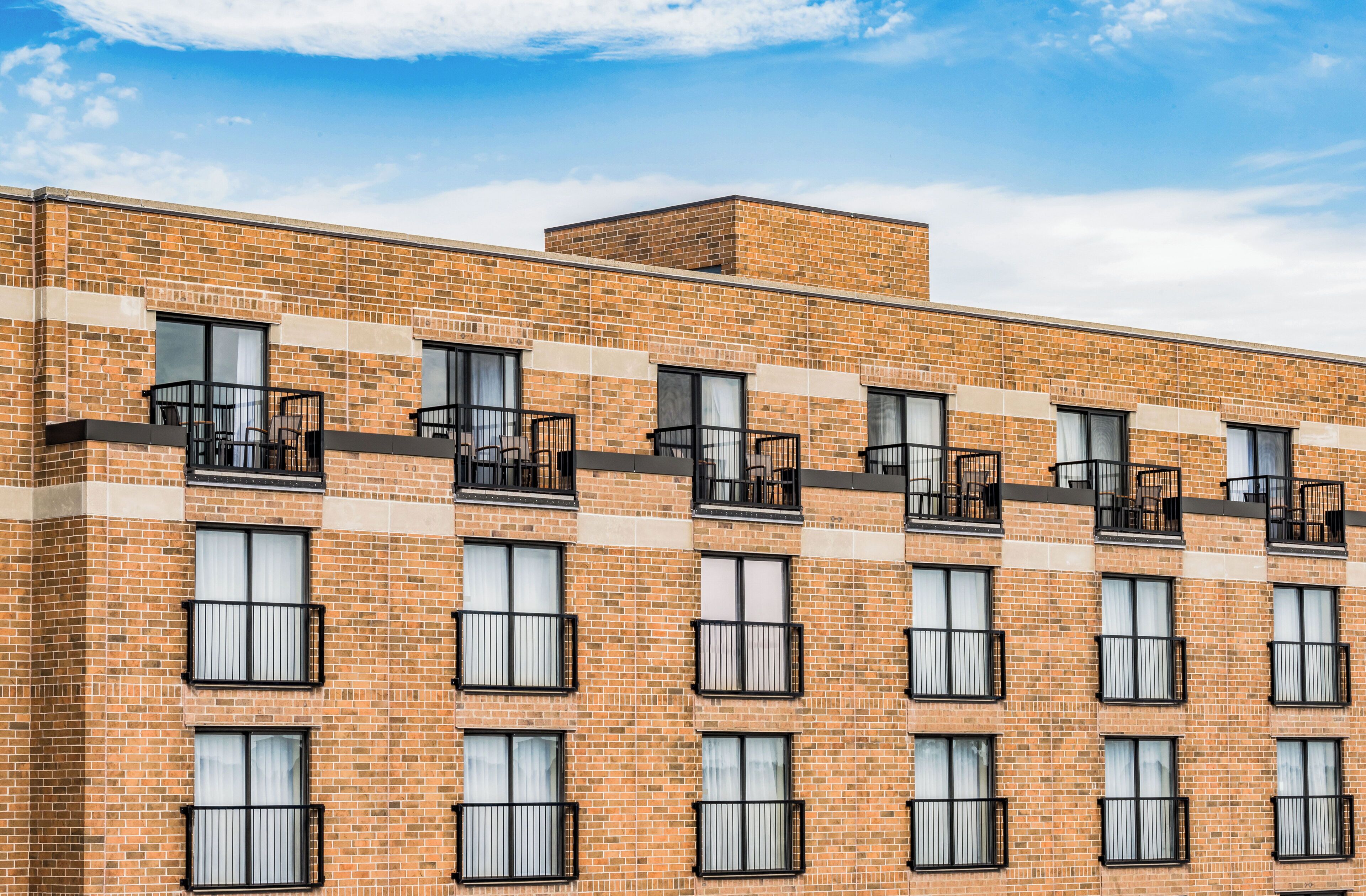 A multi-story brick building with balconies and large windows.